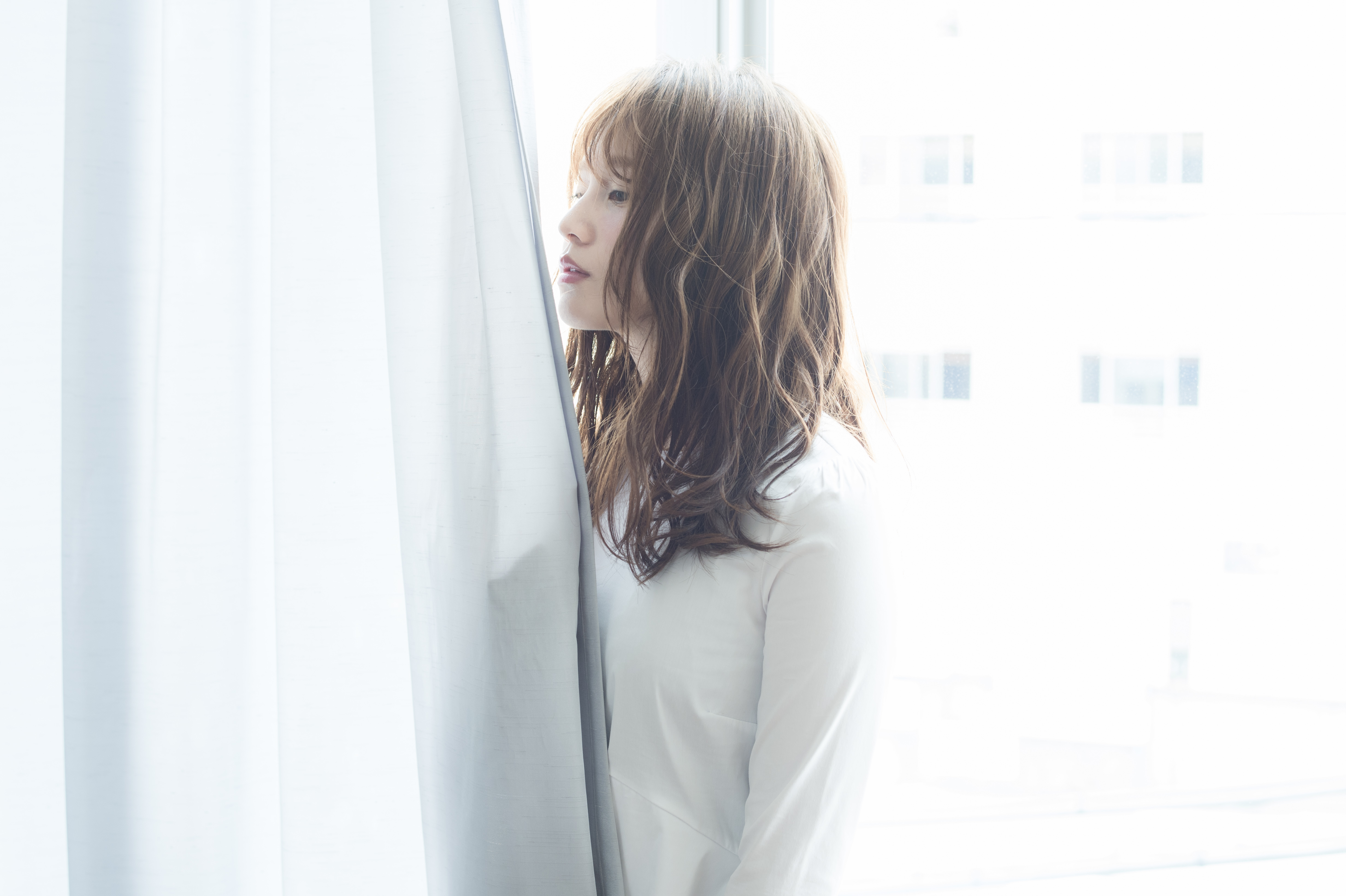 明るい窓辺で自然なまとまりのある髪を見せる女性のイメージ